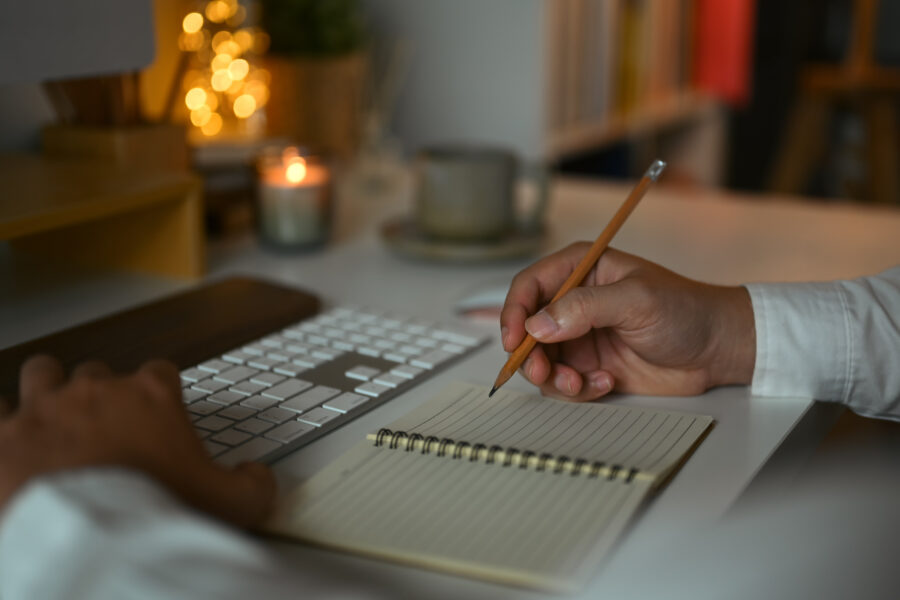 Closeup businessman writing notes in personal daily planner, planning workday at desk